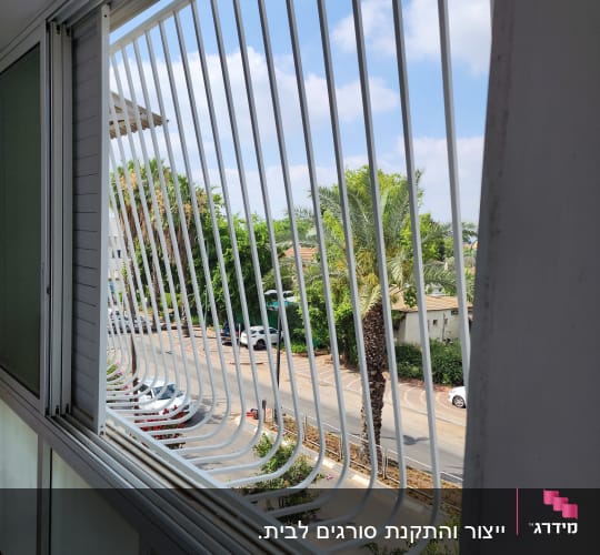 סורגים לבנים על חלון פתוח עם נוף חיצוני